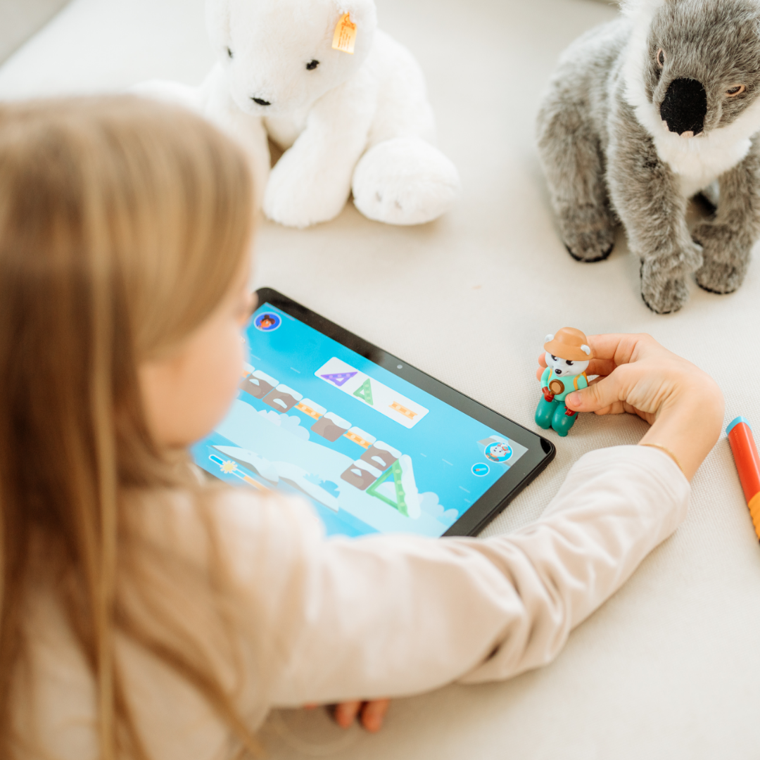 Ein Kind spielt mit dem Asa "Welt der Tiere"-Set von Edurino DE - einem Tablet und Spielzeugfiguren - umgeben von Plüschtieren, perfekt für kleine Entdecker, um spielerisch Natur und Nachhaltigkeit zu entdecken.
