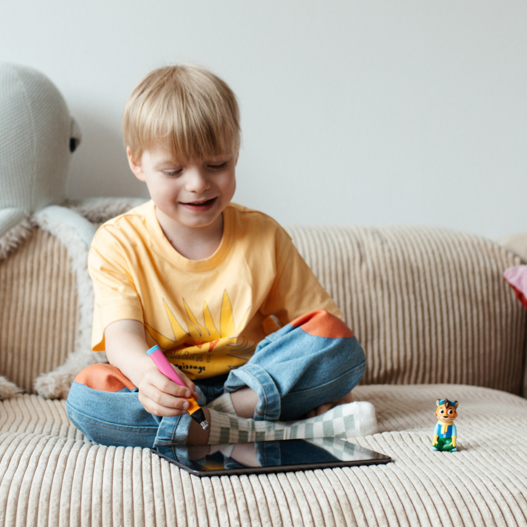 Ein kleiner Junge sitzt im Schneidersitz auf einer beigen Couch und zeichnet mit einem Stift auf dem Leo "Meine Gefühle"-Tablett von Edurino DE - Empathie und soziale Stärke durch kreativen Ausdruck fördern.