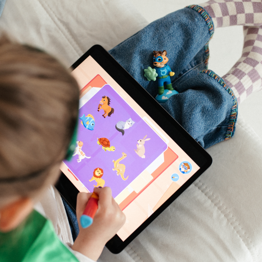 Ein Kind benutzt einen Edurino DE Leo "Freundschaft & Soziales"-Stift, um mit einer Spielzeugfigur an seiner Seite ein Tierzuordnungsspiel zu spielen - und fördert so soziale Fähigkeiten und Empathie durch interaktives digitales Spiel.