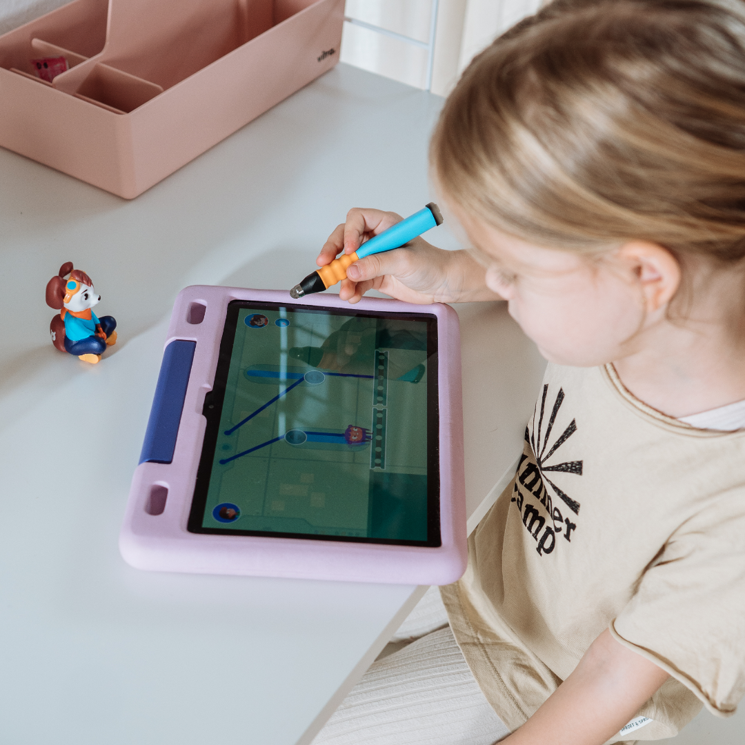 Ein Kind benutzt einen Stift auf einem Tablet, um mit dem Luca "Logisches Denken & Coding" von Edurino DE zu spielen, während eine Spielzeugfigur auf dem Tisch daneben steht.