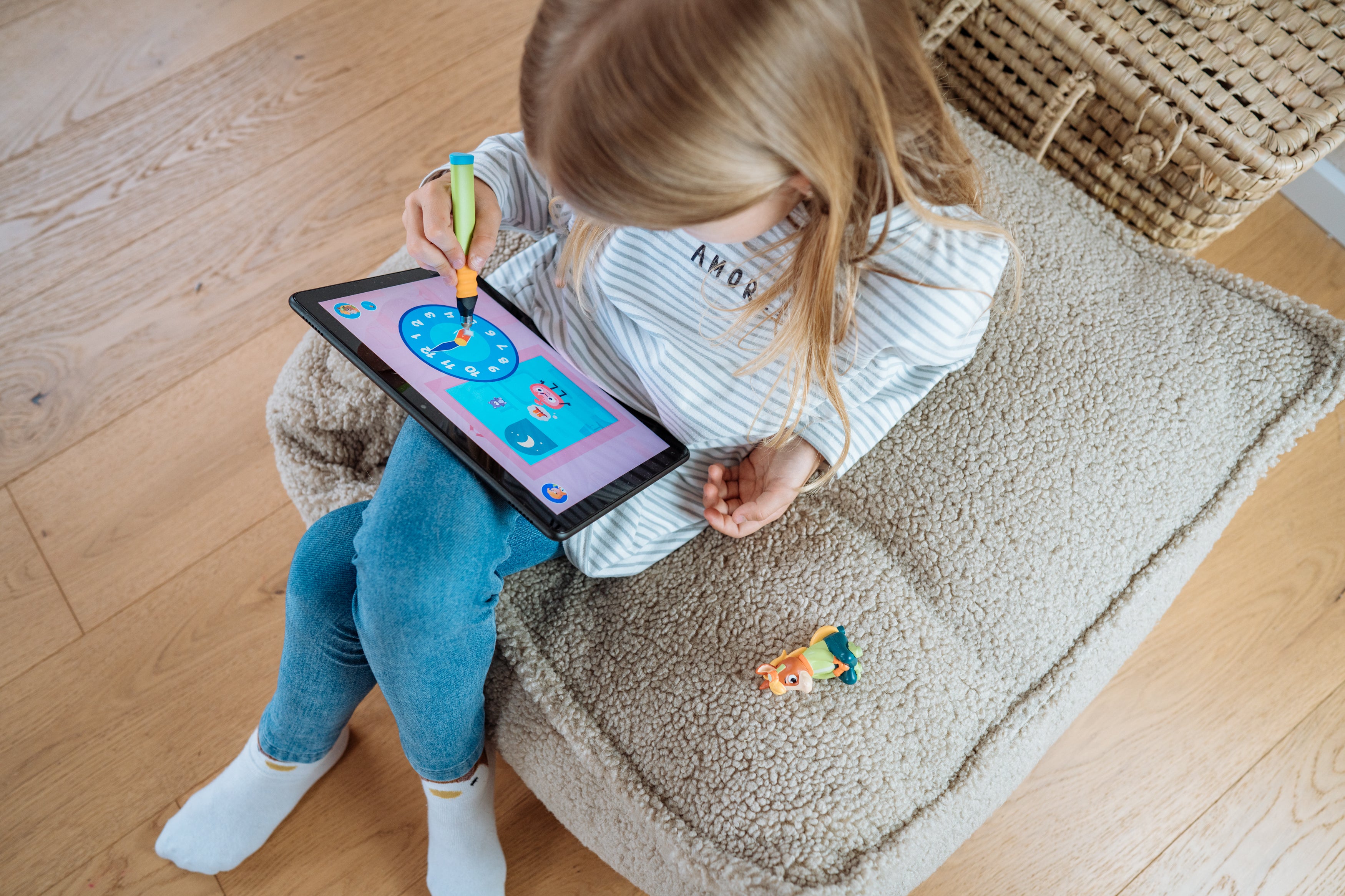 Mädchen am Tablet spielt ein Spiel. Auf dem Bildschirm eine Uhr.